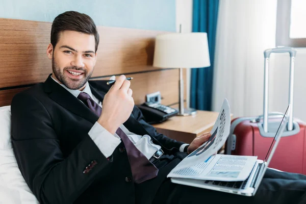 Uomo d'affari sorridente che tiene il giornale e guarda la macchina fotografica — Foto stock