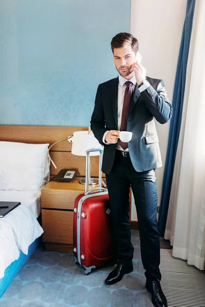 Homem de negócios bonito falando por smartphone no quarto de hotel — Fotografia de Stock