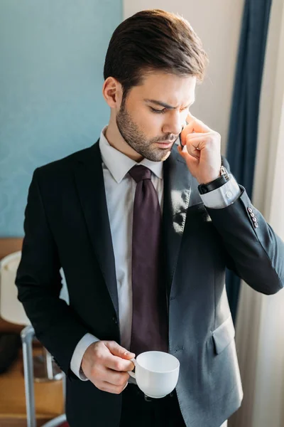 Hombre de negocios guapo hablando por teléfono inteligente en la habitación de hotel - foto de stock