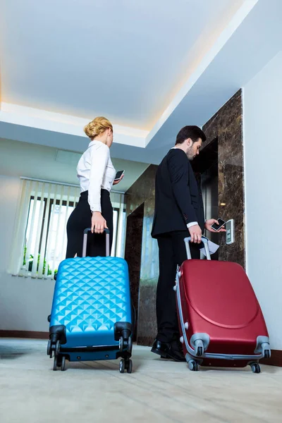 Vista inferior de hombre de negocios y mujer de negocios esperando ascensor en el hotel - foto de stock