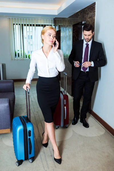 Beautiful businesswoman talking by smartphone in hotel corridor — Stock Photo