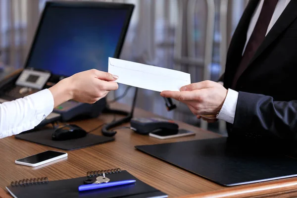 Cropped image of receptionist giving envelope to businessman in hotel — Stock Photo