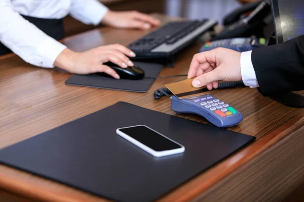 Imagen recortada del hombre de negocios que paga con tarjeta de crédito en recepción en el hotel - foto de stock