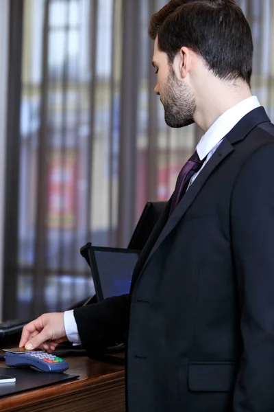 Вид сбоку бизнесмена, расплачивающегося кредитной картой в отеле — стоковое фото