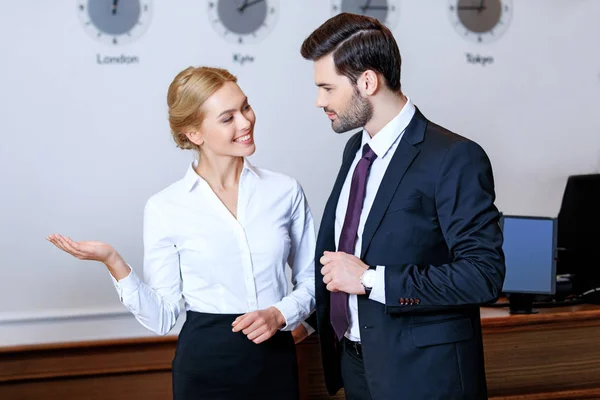 Recepcionista sorrindo apontando algo para o empresário — Fotografia de Stock