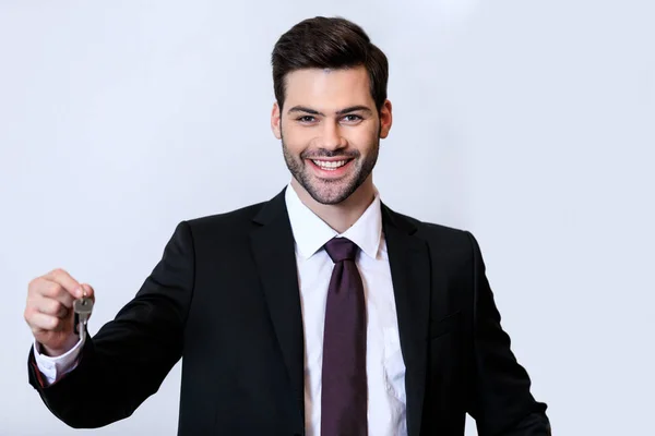 Smiling handsome receptionist holding key isolated on white — Stock Photo