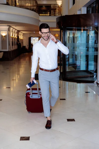 Viajante bonito andando no hotel e falando por smartphone — Fotografia de Stock