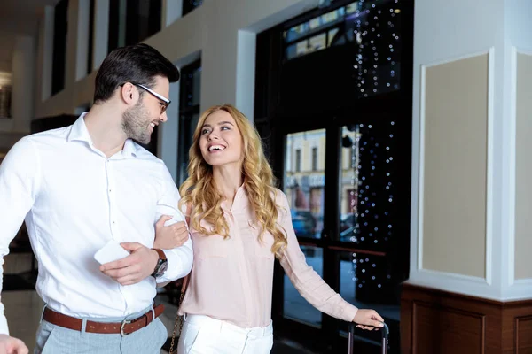 Happy couple of travelers walking with luggage in hotel — Stock Photo