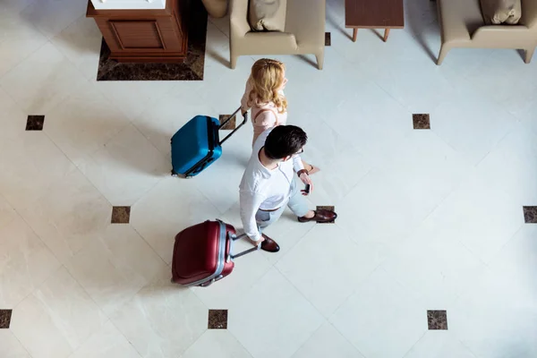 Overhead view of couple of travelers walking with luggage in hotel — Stock Photo