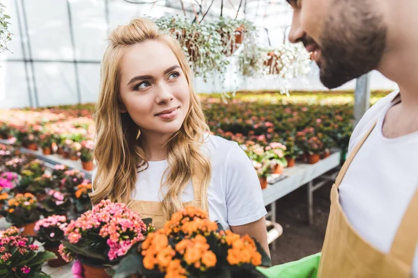 Young male and female gardeners holding pots with flowers — Stock Photo