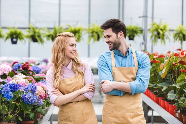 Hommes et femmes propriétaires de serre parmi les fleurs — Photo de stock