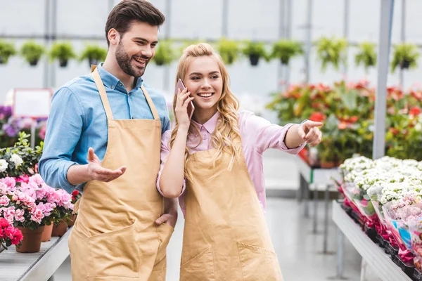 Bonito jardineiro masculino por mulher falando no telefone em estufa — Fotografia de Stock