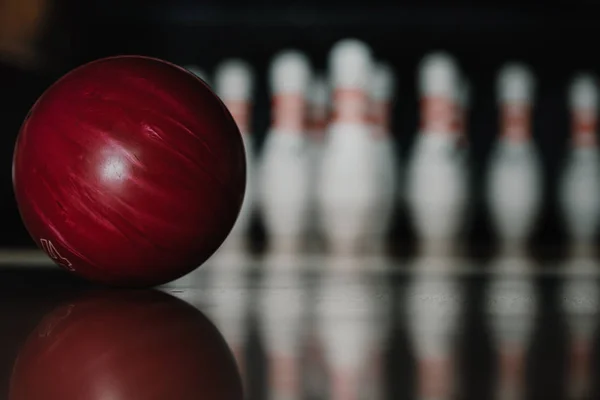 Close-up shot of red bowling ball on alley in front of pins — Stock Photo