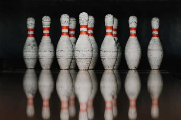 Grungy bowling pins in gate with reflection in polished floor — Stock Photo