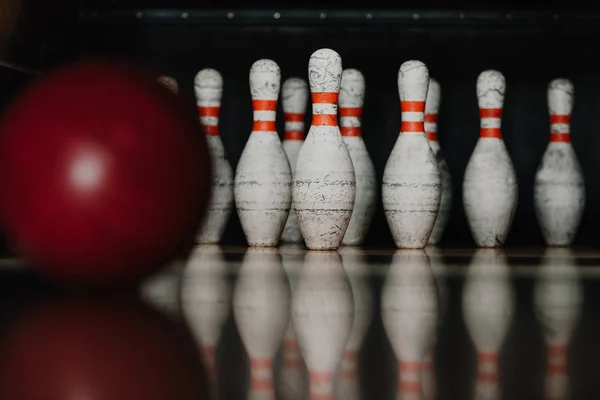 Pinos de boliche grungy com bola vermelha em primeiro plano — Fotografia de Stock