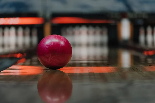 Gros plan de boule de bowling rouge couchée sur l'allée sous la lumière chaude — Photo de stock