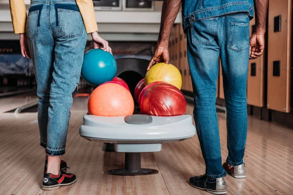Colpo ritagliato di coppia multietnica con palle da bowling in piedi di fronte a vicoli al club — Foto stock