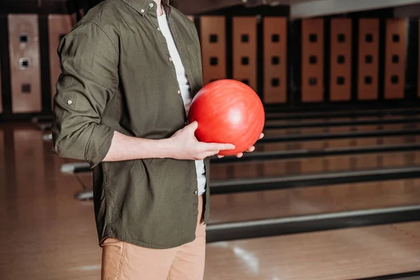Обрезанный снимок человека, держащего шар для боулинга в клубе — стоковое фото