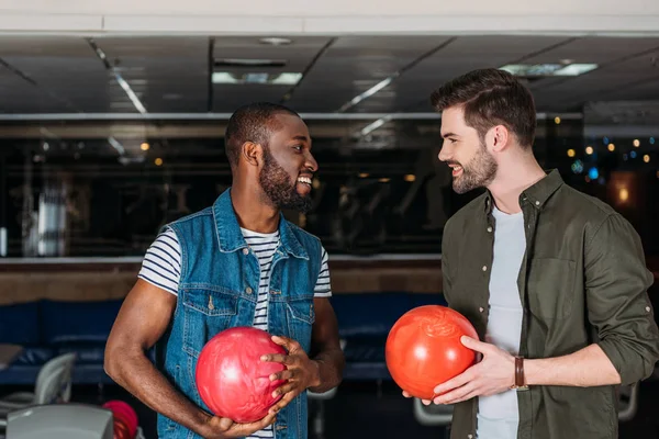 Heureux jeunes hommes avec des boules au bowling club — Photo de stock