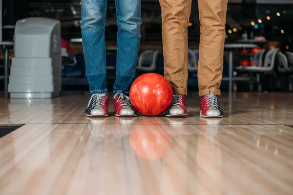 Tiro cortado de homens de pé na frente da pista de boliche com bola — Fotografia de Stock