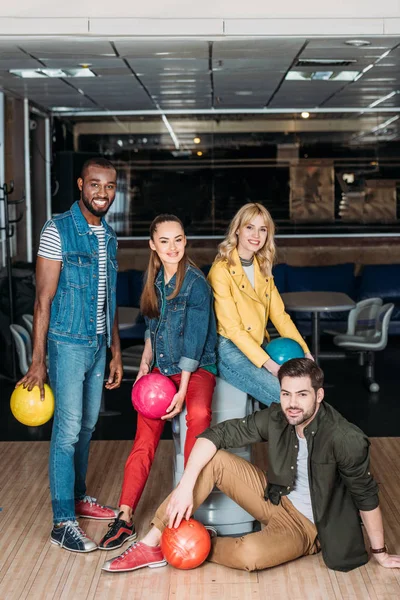 Grupo de jóvenes amigos posando con bolas juntos en el club de bolos - foto de stock