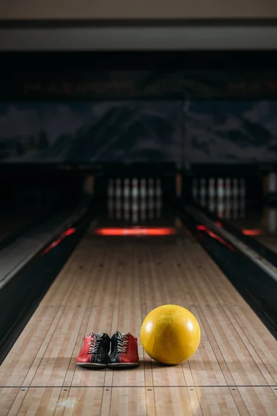 Gelbe Bowlingkugel mit Leihschuhen auf Kegelbahn im Club — Stockfoto