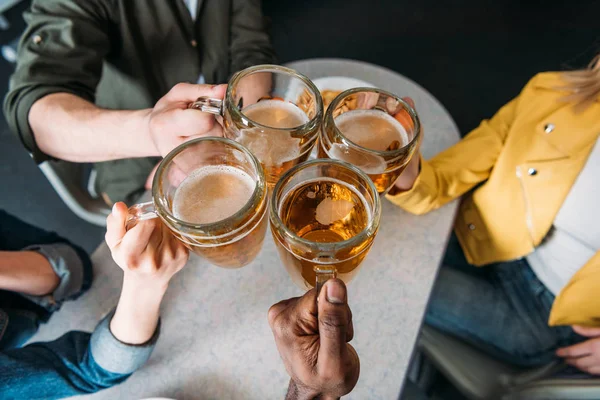 Abgeschnittene Aufnahme einer Gruppe von Freunden, die Bierkrüge klingeln — Stockfoto