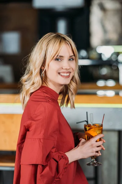 Щаслива молода жінка з коктейлем проводить час у барі — стокове фото