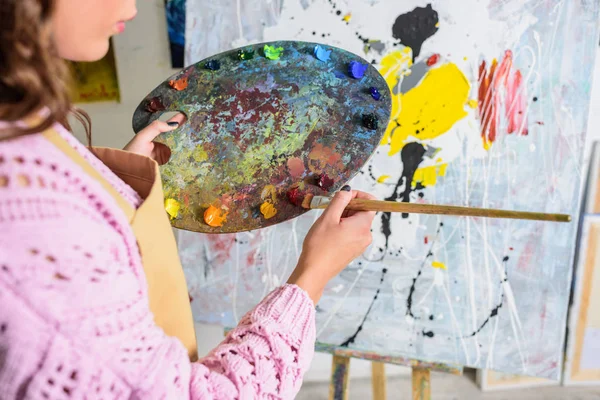 Imagem recortada de artista feminina tirando tinta da paleta em oficina — Fotografia de Stock