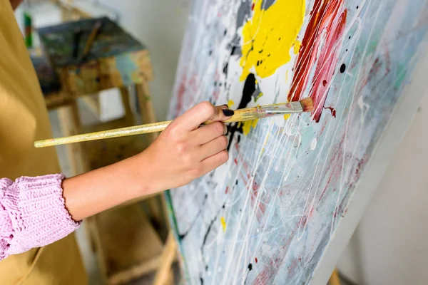 Cropped image of female artist painting in workshop with painting brush — Stock Photo