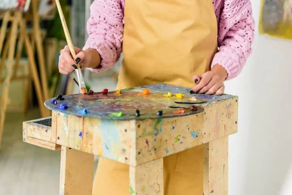 Image recadrée de l'artiste féminine appliquant des peintures sur la palette en atelier — Photo de stock