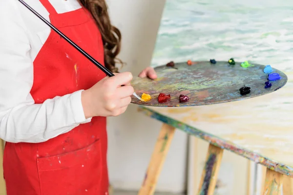 Imagen recortada de niño tomando pintura de la paleta en el taller de la escuela de arte - foto de stock