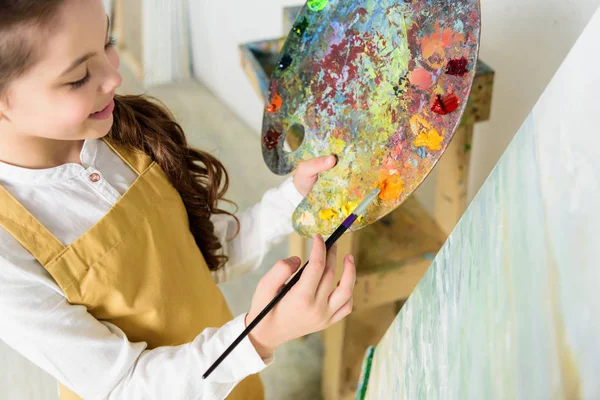 High angle view of kid taking paint from palette in workshop of art school — Stock Photo