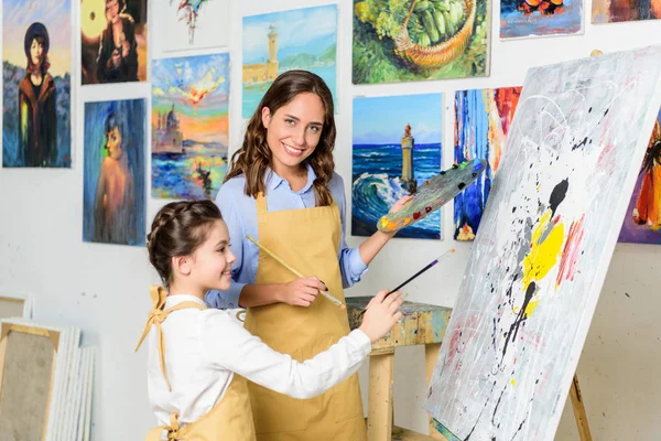 Professeur souriant et élève peinture dans l'atelier de l'école d'art — Photo de stock