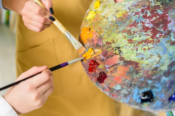 Zugeschnittenes Bild von Lehrer und Schüler, die in der Werkstatt der Kunstschule die gleiche Farbe aus der Palette nehmen — Stockfoto