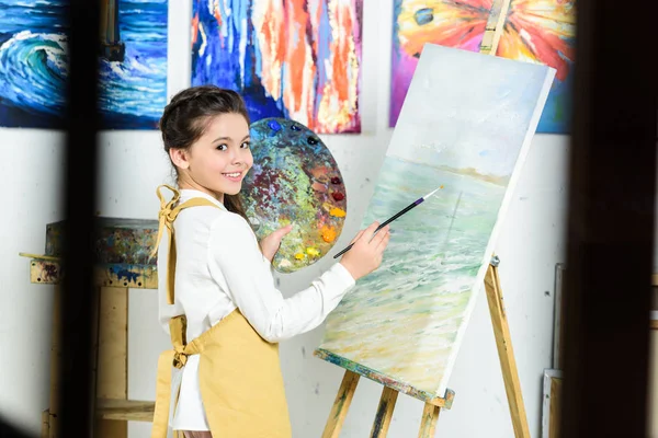 Seitenansicht der Kindermalerei und Palette halten in der Werkstatt der Kunstschule — Stockfoto