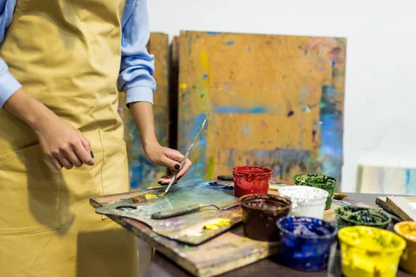 Zugeschnittenes Bild eines Künstlers, der in der Werkstatt Farbe mit Pinsel aus der Palette nimmt — Stockfoto