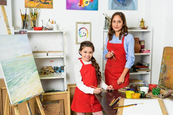 Happy teacher and pupil looking at camera in workshop of art school — Stock Photo