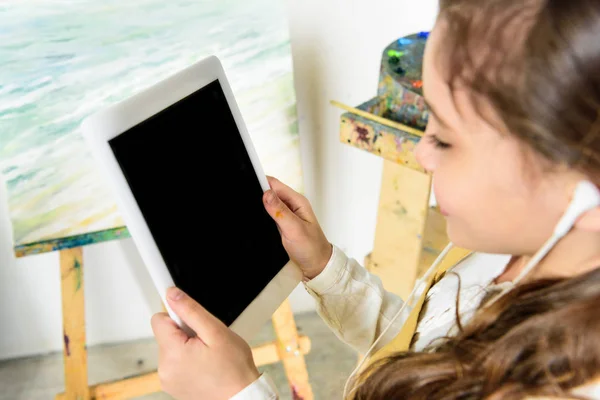 Criança ouvindo música com tablet na oficina da escola de arte — Fotografia de Stock