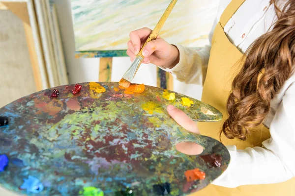 Imagem cortada da criança que toma pinturas a óleo da paleta na oficina da escola de arte — Fotografia de Stock
