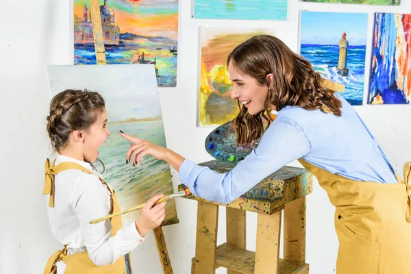 Smiling teacher touching pupil nose in workshop of art school — Stock Photo