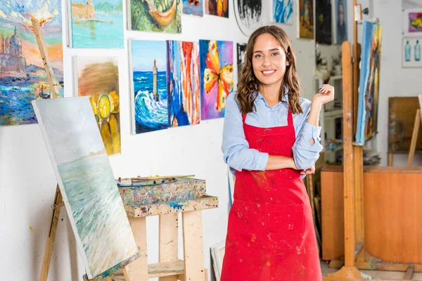 Hermosa artista femenina de pie y mirando a la cámara en el taller - foto de stock