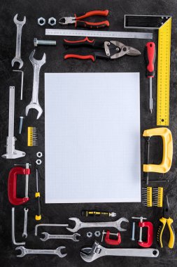 top view of set of various work tools and blank paper on black clipart