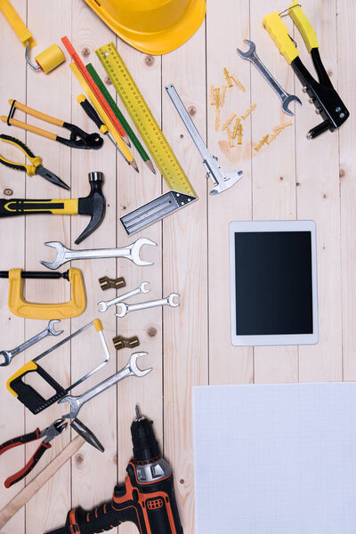 Top view of different tools with blueprint and digital tablet on wooden tabletop 