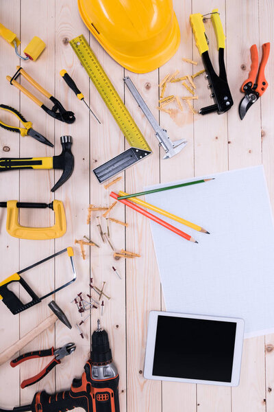 Top view of different tools with blueprint and digital tablet on wooden tabletop 
