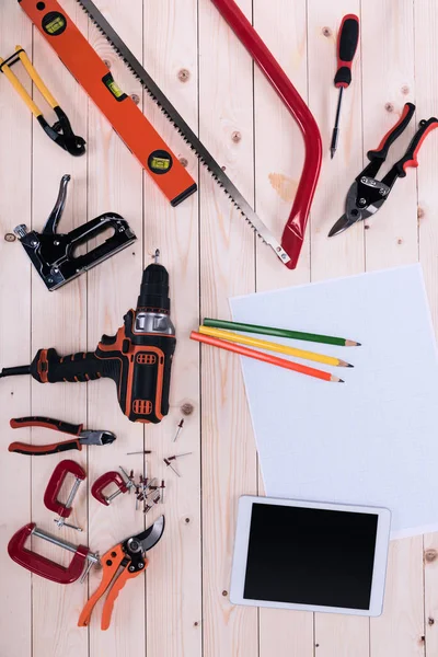 Top view of different tools with blueprint and digital tablet on wooden tabletop — Free Stock Photo