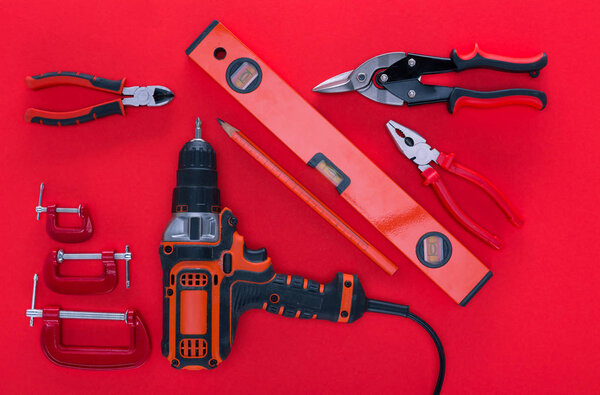 top view of various work tools and pencil on red