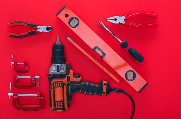top view of various work tools and pencil on red
