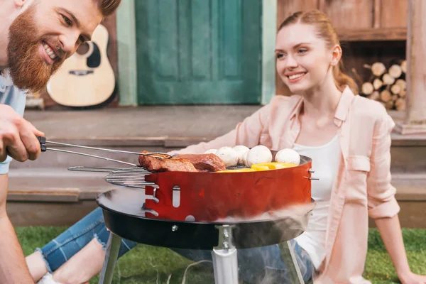 Couple grilling meat and vegetables — Stock Photo, Image