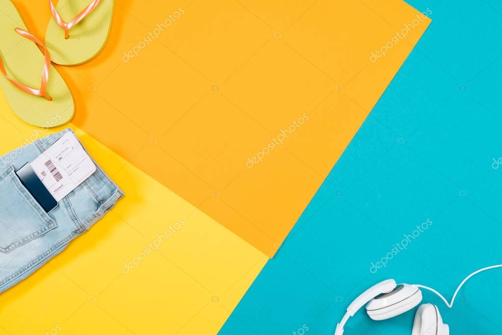 Summer vacation background with headphones, flip flops, denim trousers, ticket, passport with copy space